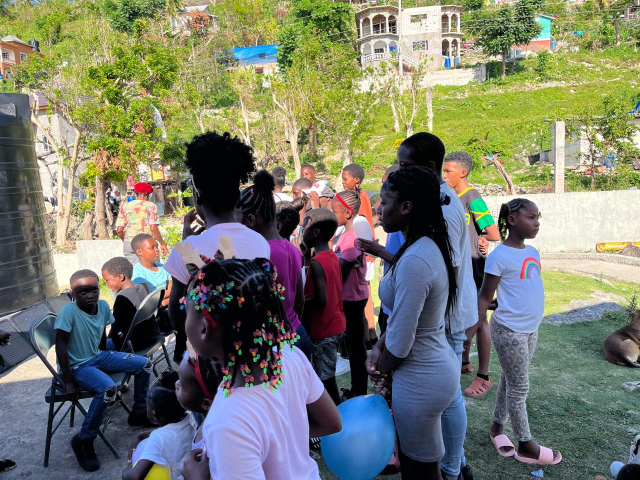 Children and adults gather in a community area, with some engaging in festive activities, highlighting a local celebration or event.