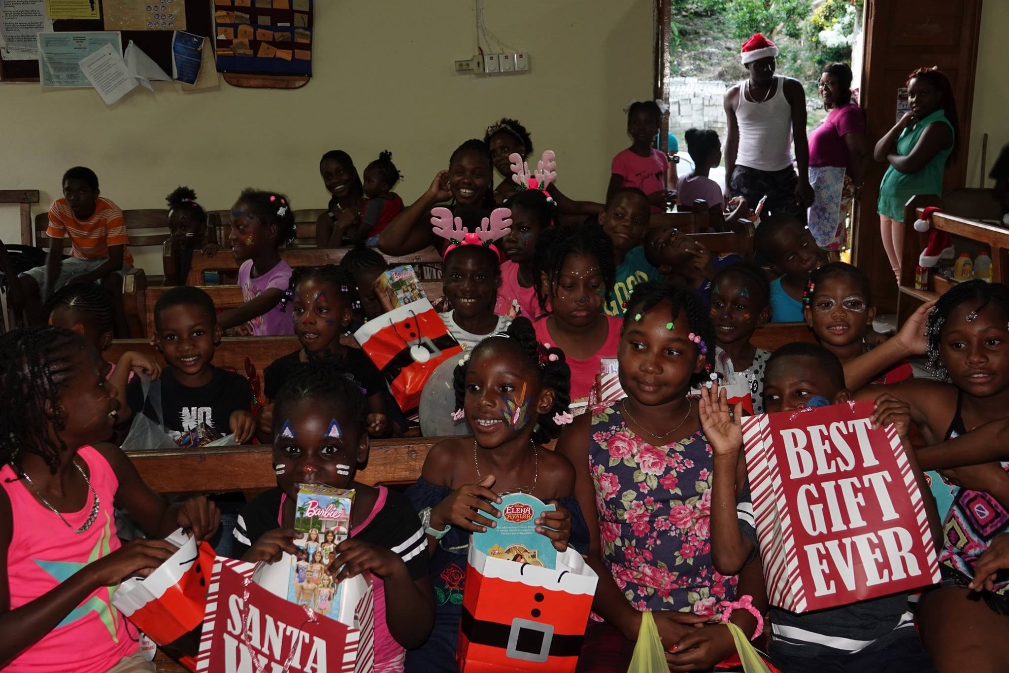 Children joyfully celebrate a festive event, holding gifts and smiling, with decorations and friends around them, highlighting community joy.